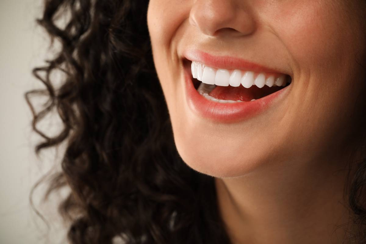 Smiling woman on light grey background, closeup.